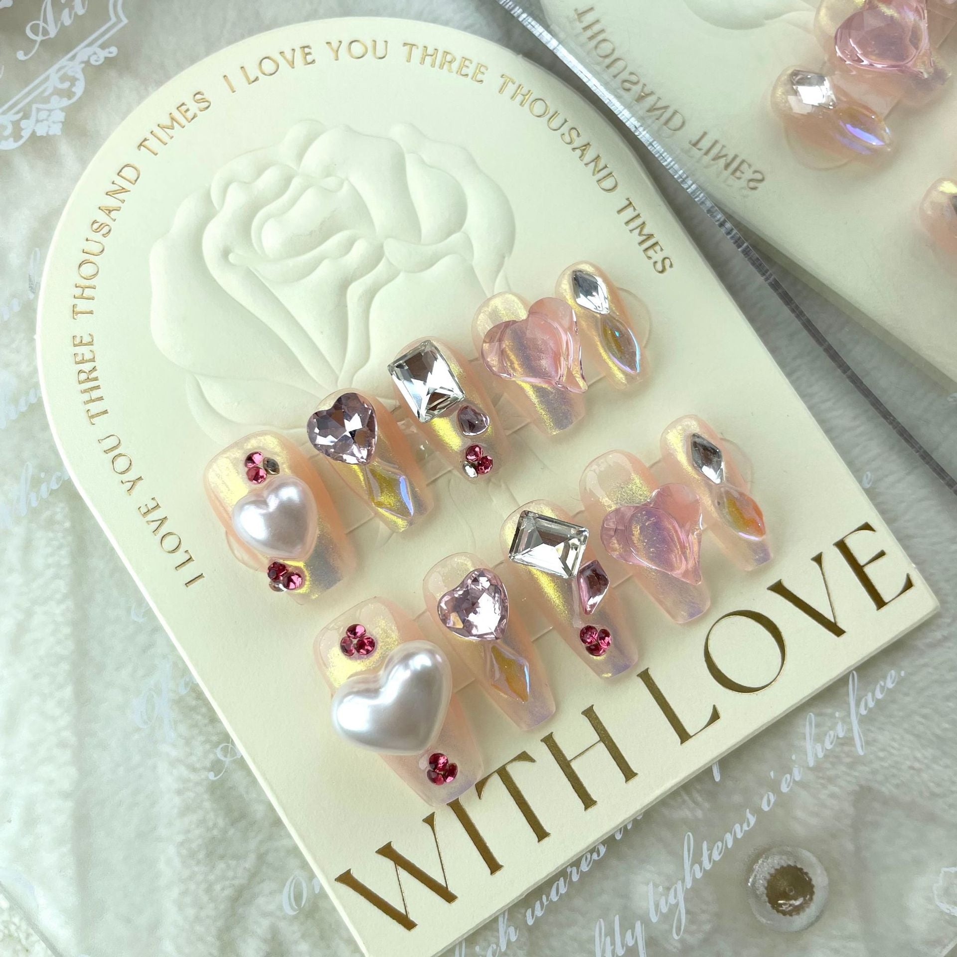 ongles long avec motifs en 3d coeur blanc et rose, strass gris argenté, strass rose