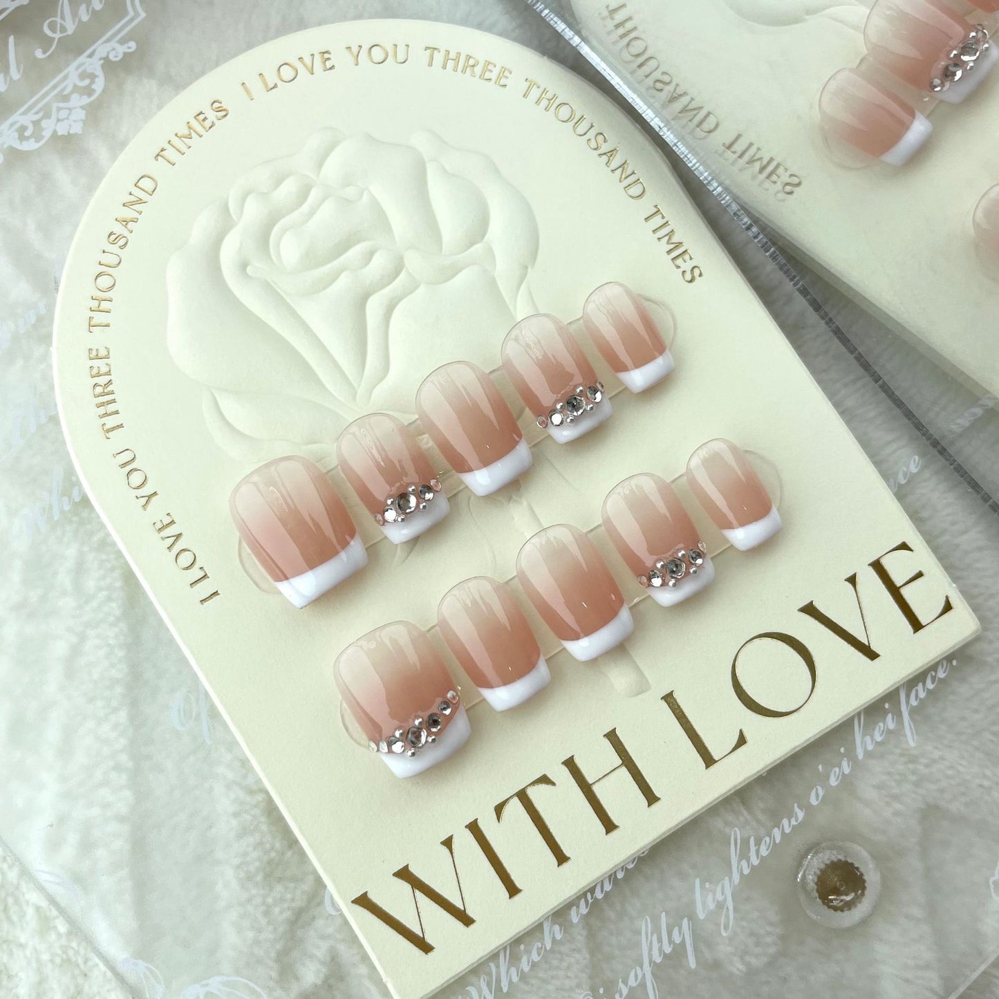 ongles nude couleur clair et blanc avec strass gris simple