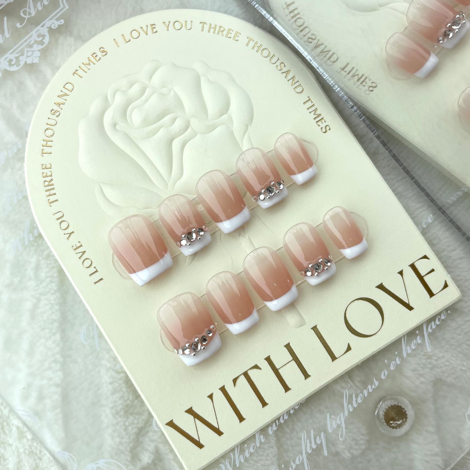 ongles nude couleur clair et blanc avec strass gris simple